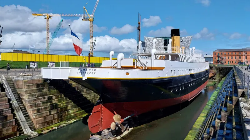 Le Nomadic, restaur&eacute; et de retour dans la ville o&ugrave; il a &eacute;t&eacute; construit, photographi&eacute; le 14 avril 2024, journ&eacute;e comm&eacute;morative des 112 ans du naufrage du Titanic. Le drapeau fran&ccedil;ais y flotte toujours. En arri&egrave;re-plan, les &eacute;traves effil&eacute;es du mus&eacute;e Titanic Quarter de Belfast, en Irlande du Nord.