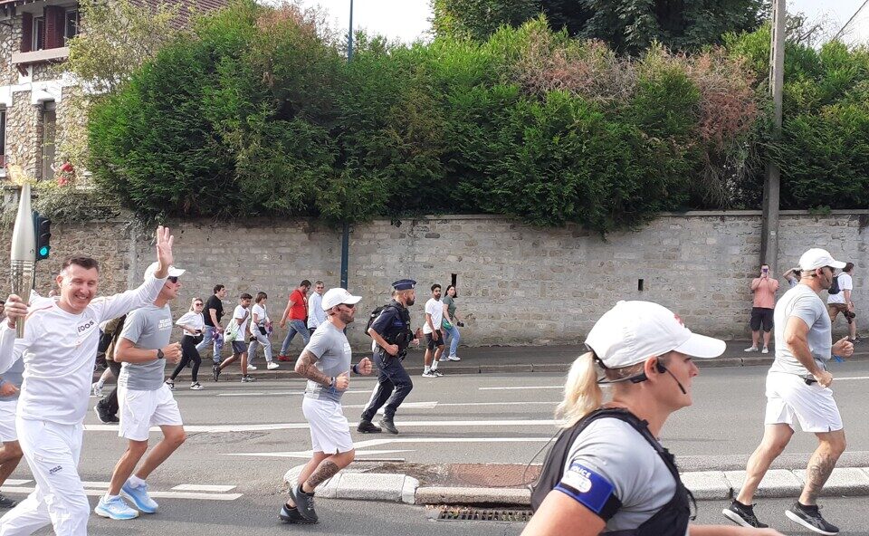 La flamme gravit l'avenue du général-Gabriel-Delarue, à Pontoise, avec son porteur, son staff et ses spectateurs.