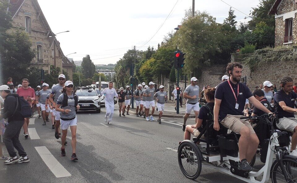 La flamme gravit l'avenue du général-Gabriel-Delarue, à Pontoise, avec son porteur, son staff et ses spectateurs.