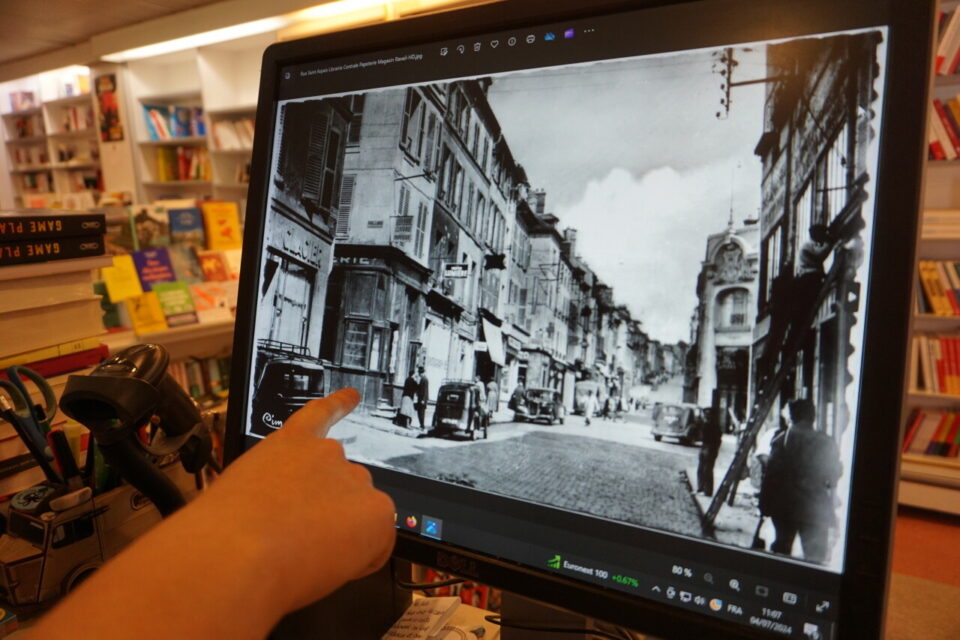 Camille d&eacute;signe une ancienne photographie de la rue Saint-Aspais o&ugrave; l'on y aper&ccedil;oit l'entr&eacute;e de la libraire de l'Escalier.