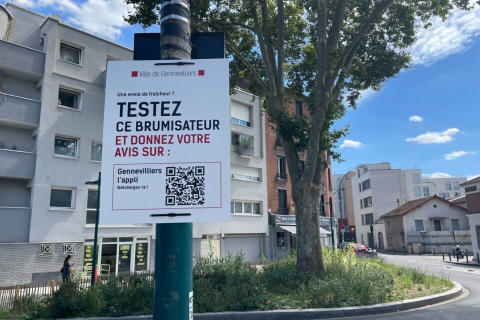 Juste à côté du brumisateur, une pancarte encourage les habitants à donner leur avis sur l'application mobile de la commune de Gennevilliers.