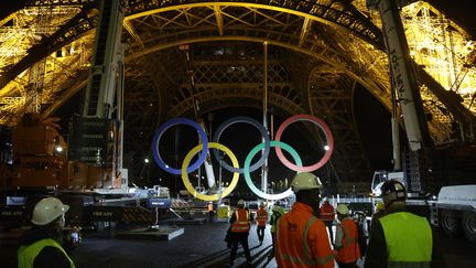 Des ouvriers regardent des grues retirer les anneaux olympiques de la Tour Eiffel &agrave; Paris, le 27 septembre 2024. (GEOFFROY VAN DER HASSELT / AFP)