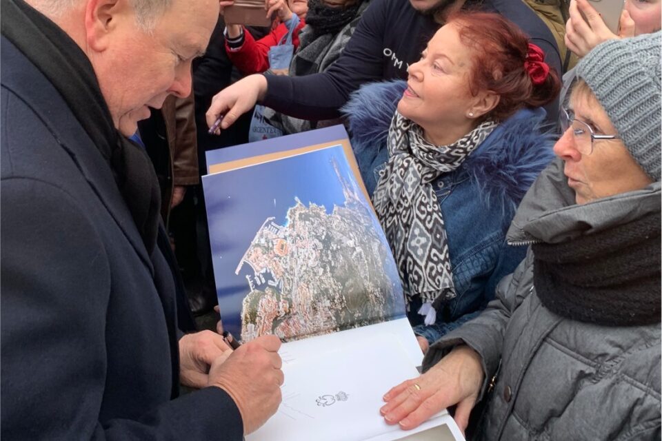 Sur le livre qu'est en train de signer le prince, on voit vu du ciel, le rocher à gauche, la princesse Grace, mère d'Albert II à droite.