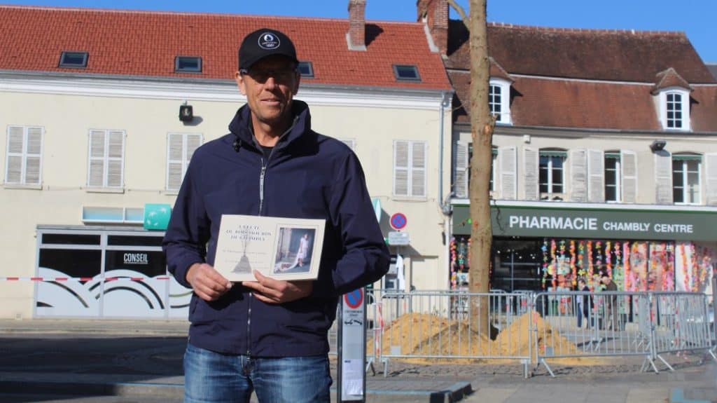 Patrick Duros pose devant le Car&ecirc;mpremant avec son livre sur l'histoire du Bois-Hourdy de Chambly.